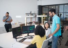 Office employees collaborate on financial data at modern workspace, engaging in teamwork and communication.