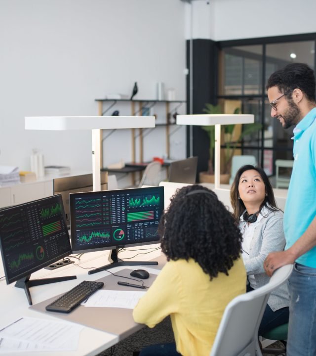 Office employees collaborate on financial data at modern workspace, engaging in teamwork and communication.